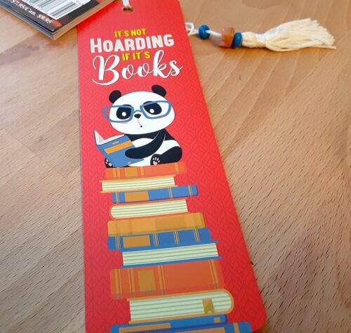 It's Not Hoarding If It's Books Bookmark. A cute panda wearing glasses reads while sitting on top of a stack of books. Bright red background.